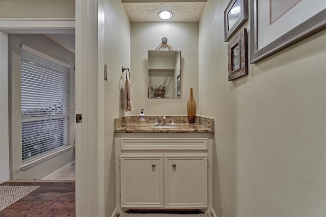 bathroom with vanity, a textured ceiling, and baseboards