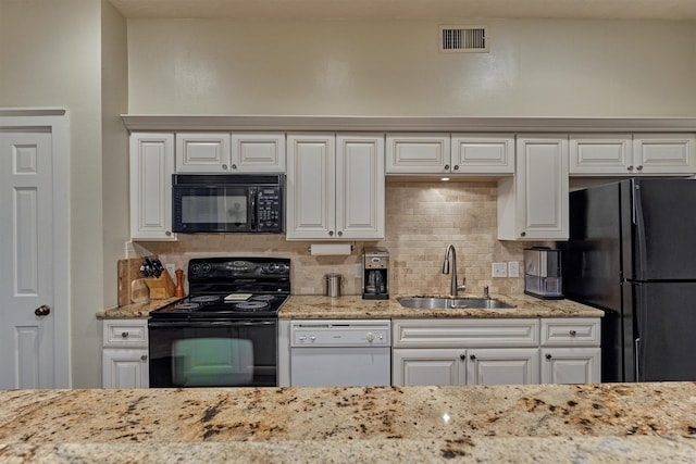 kitchen with visible vents, a sink, black appliances, decorative backsplash, and light stone counters