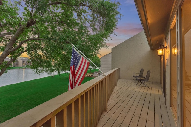 deck with a water view and a lawn