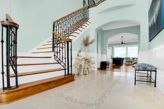 20710 E Sunset Bay Dr, Galveston, TX 77554 - stairs featuring arched walkways, a wainscoted wall, a decorative wall, and a high ceiling