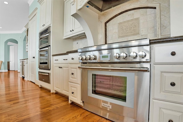 20710 E Sunset Bay Dr, Galveston, TX 77554 - kitchen featuring a warming drawer, crown molding, stainless steel appliances, dark countertops, and light wood-style flooring