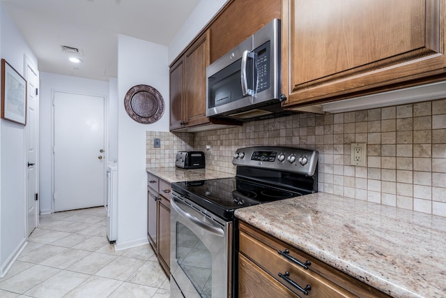 150 Gessner Rd Unit 7D, Houston, TX 77024 - kitchen with appliances with stainless steel finishes, light tile patterned floors, light stone counters, decorative backsplash, and recessed lighting
