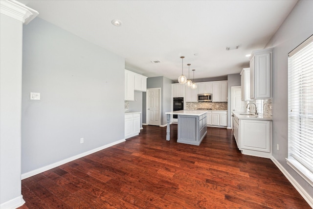 kitchen featuring tasteful backsplash, a center island, a sink, and stainless steel microwave