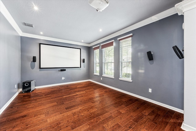 home theater with crown molding, visible vents, wood finished floors, and baseboards