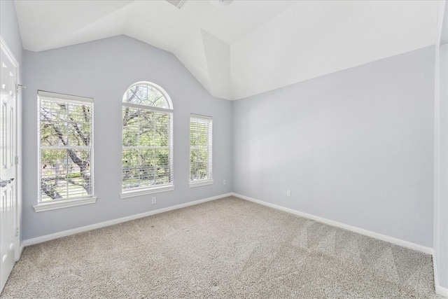 unfurnished room featuring carpet flooring, vaulted ceiling, and baseboards