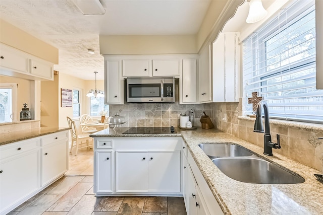 18210 Point Lookout Dr, Houston, TX 77058 - kitchen with stainless steel microwave, a sink, black electric cooktop, and white cabinets