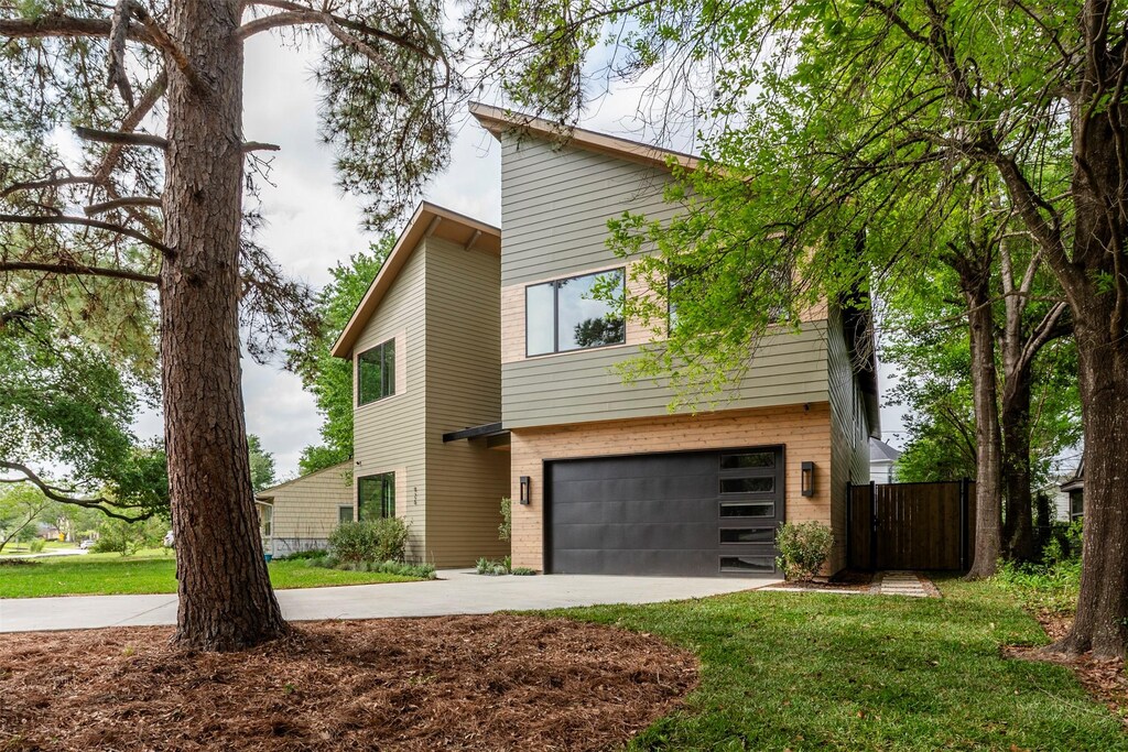 926 W 41st St, Houston, TX 77018 - view of side of property featuring a lawn, a garage, brick siding, and concrete driveway