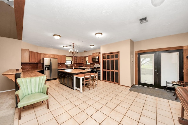 3810 Peters San Felipe Rd, Sealy, TX 77474 - kitchen featuring a kitchen bar, appliances with stainless steel finishes, light countertops, decorative backsplash, and a notable chandelier