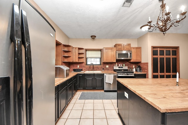 3810 Peters San Felipe Rd, Sealy, TX 77474 - kitchen with tasteful backsplash, light tile patterned floors, open shelves, a sink, and stainless steel appliances