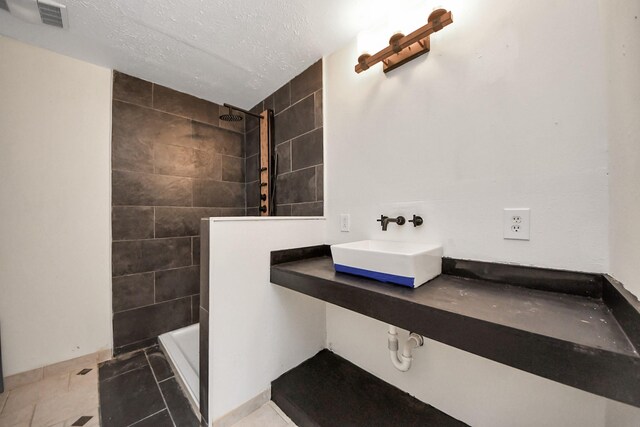 3810 Peters San Felipe Rd, Sealy, TX 77474 - full bath with baseboards, a textured ceiling, tiled shower, visible vents, and a sink