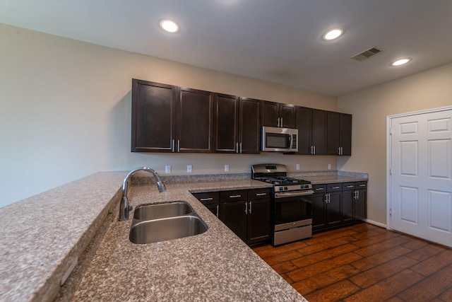 17035 Wilthorne Gardens Ct, Houston, TX 77084 - kitchen featuring dark brown cabinets, a sink, stainless steel appliances, visible vents, and dark wood-style floors