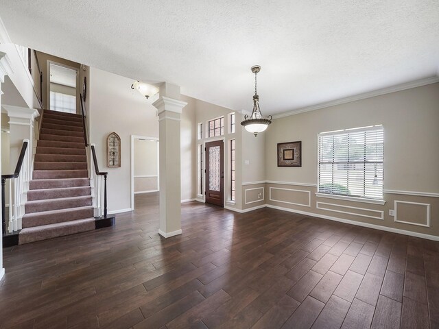 2202 Canterbury Ct, Deer Park, TX 77536 - entryway featuring decorative columns, dark wood-style flooring, a textured ceiling, stairs, and a wainscoted wall
