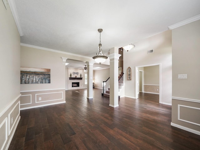 2202 Canterbury Ct, Deer Park, TX 77536 - unfurnished living room with decorative columns, dark wood finished floors, a fireplace, ornamental molding, and stairs