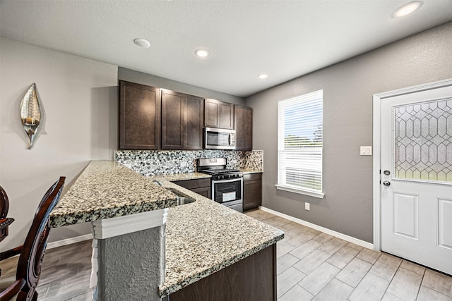 24818 Russet Bluff Trl, Houston, TX 77336 - kitchen with decorative backsplash, light wood-style flooring, a peninsula, stainless steel appliances, and dark brown cabinetry
