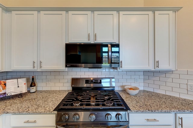 12006 Wooden Mill Ln, Santa Fe, TX 77510 - kitchen with white cabinetry, decorative backsplash, appliances with stainless steel finishes, and light stone counters