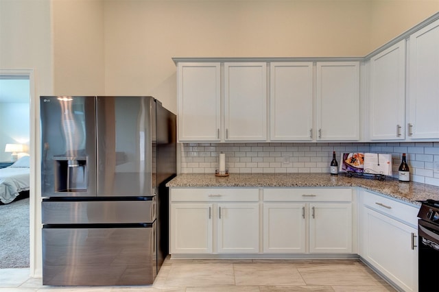 12006 Wooden Mill Ln, Santa Fe, TX 77510 - kitchen with light stone counters, stainless steel fridge with ice dispenser, backsplash, and white cabinets