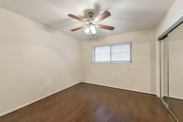 10607 Longmont Dr, Houston, TX 77042 - unfurnished bedroom with a closet, dark wood finished floors, baseboards, a ceiling fan, and a textured ceiling
