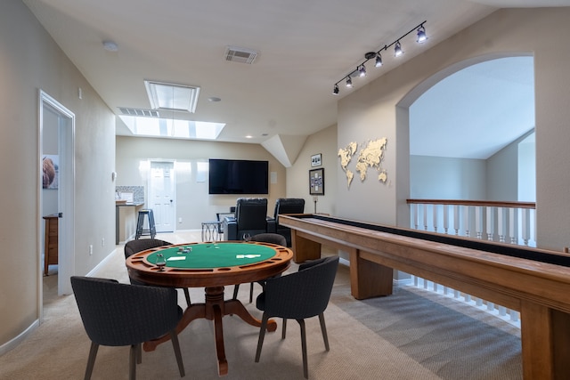 rec room with vaulted ceiling, light carpet, a skylight, arched walkways, and baseboards