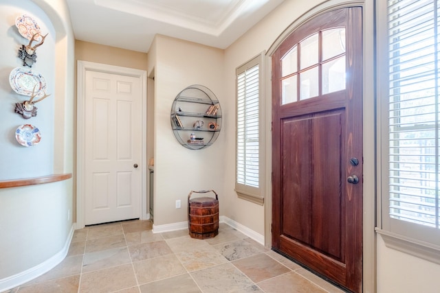 entryway with plenty of natural light, baseboards, crown molding, and light stone finish flooring
