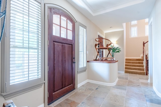 entrance foyer with stairway, baseboards, light stone finish floors, and a raised ceiling