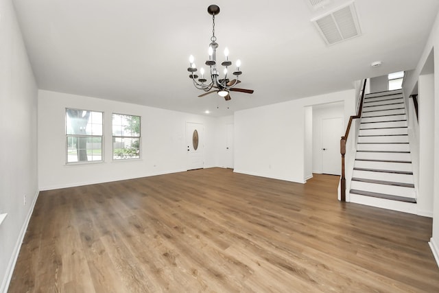 unfurnished living room featuring stairs, baseboards, visible vents, a notable chandelier, and wood finished floors