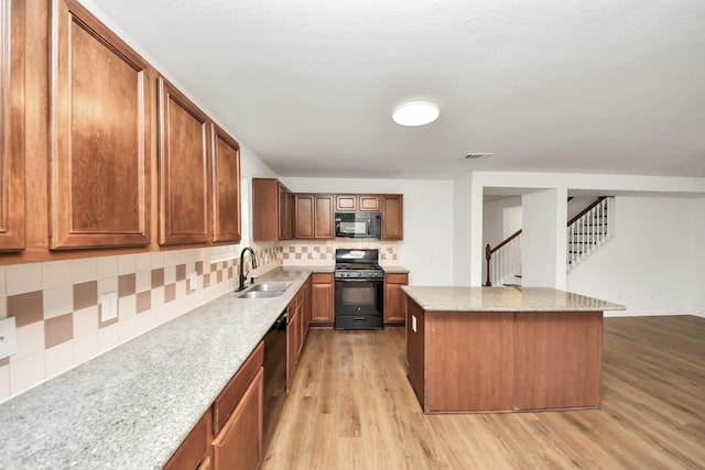 kitchen with a center island, a sink, visible vents, light wood-style flooring, and black appliances