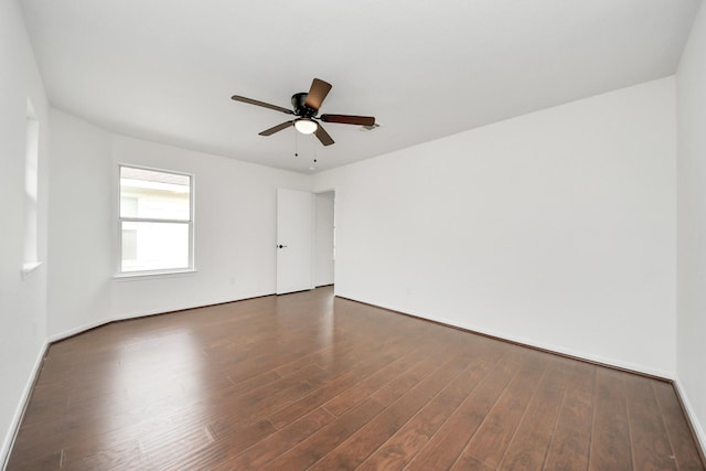 spare room featuring dark wood-style floors, baseboards, and a ceiling fan