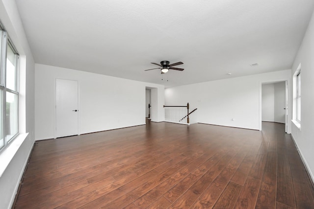 empty room with dark wood finished floors, a healthy amount of sunlight, and ceiling fan