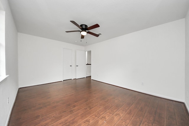 spare room with dark wood-style floors, baseboards, and a ceiling fan