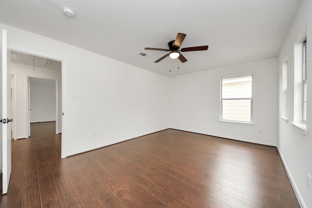 empty room featuring attic access, dark wood-style flooring, baseboards, visible vents, and a ceiling fan