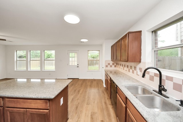 kitchen with backsplash, a sink, light wood finished floors, dishwasher, and brown cabinets