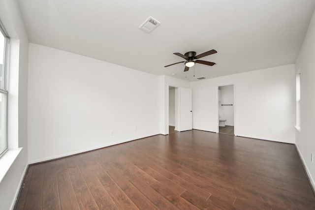 unfurnished room featuring dark wood-type flooring, baseboards, visible vents, and a ceiling fan