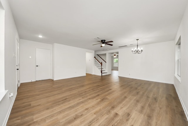 unfurnished living room with visible vents, stairway, ceiling fan with notable chandelier, and light wood finished floors