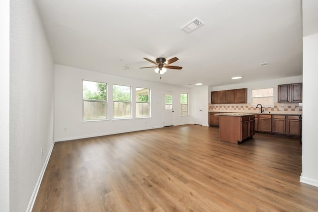 unfurnished living room featuring a sink, a ceiling fan, baseboards, visible vents, and dark wood-type flooring