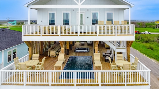 rear view of property with board and batten siding, outdoor dining area, a deck, and stairway