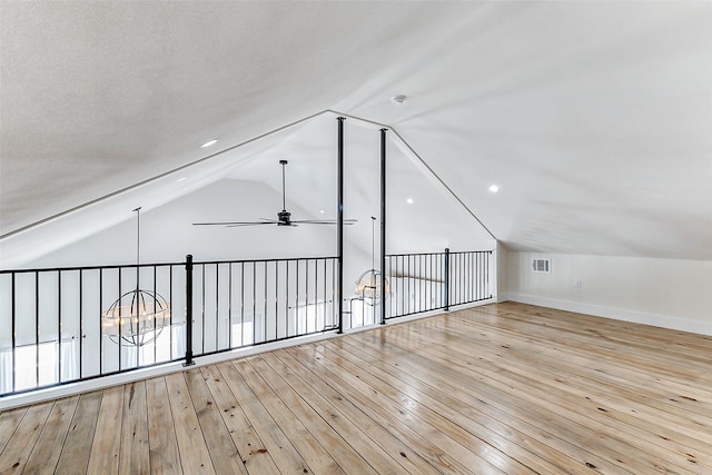 bonus room featuring lofted ceiling, wood-type flooring, baseboards, visible vents, and ceiling fan