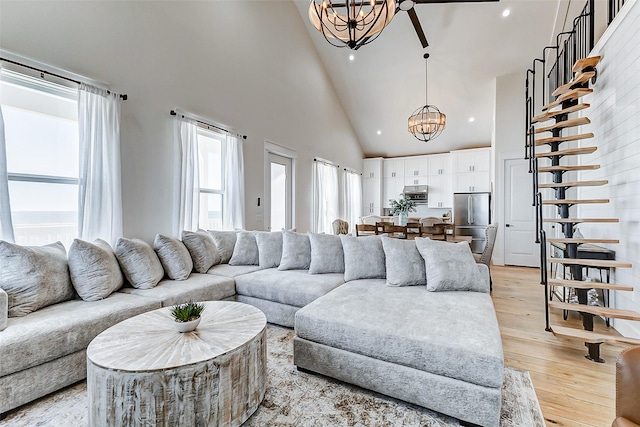 living area featuring a notable chandelier, high vaulted ceiling, light wood-style flooring, and recessed lighting