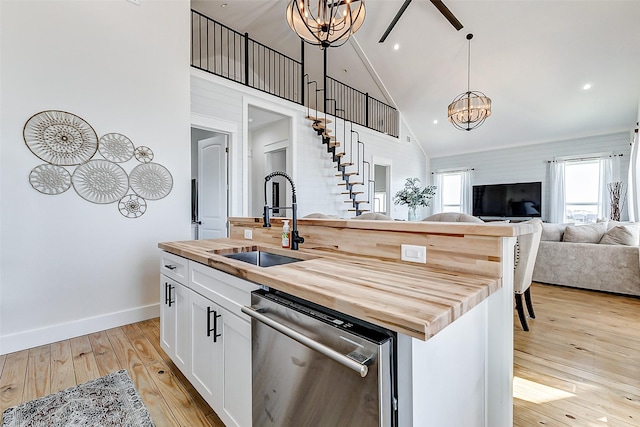 kitchen with butcher block countertops, light wood-style flooring, dishwasher, a sink, and open floor plan