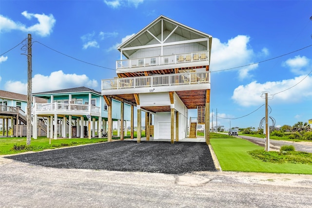 raised beach house featuring stairs, driveway, a front yard, a carport, and a garage