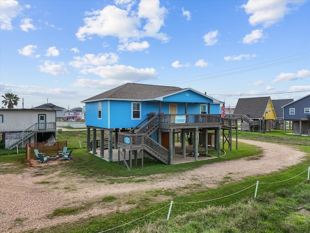 818 Surf Dr, Surfside Beach, TX 77541 - back of property featuring stairs, dirt driveway, a wooden deck, an outdoor fire pit, and a patio