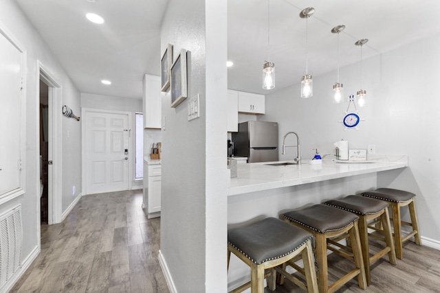 7600 Seawall Blvd Unit 214, Galveston, TX 77551 - kitchen with freestanding refrigerator, a kitchen breakfast bar, wood finished floors, white cabinetry, and a peninsula