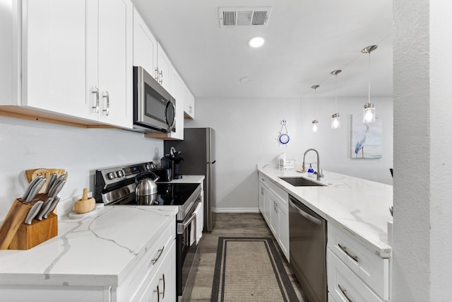7600 Seawall Blvd Unit 214, Galveston, TX 77551 - kitchen with stainless steel appliances, dark wood finished floors, white cabinets, a peninsula, and light stone countertops