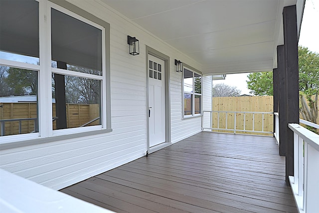 wooden deck featuring covered porch and fence