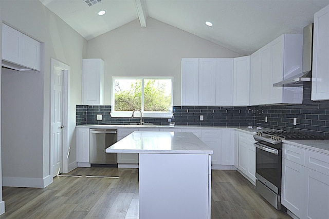 kitchen with lofted ceiling with beams, stainless steel appliances, light wood-style floors, and a center island