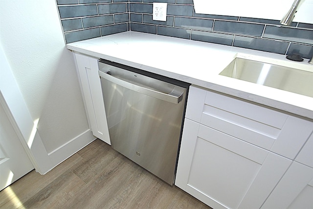kitchen featuring light wood-type flooring, light countertops, white cabinets, and stainless steel dishwasher