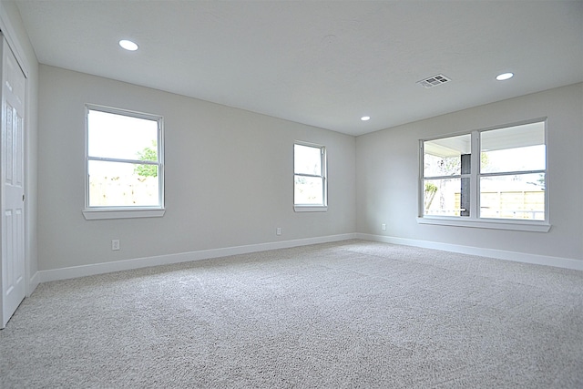 empty room featuring plenty of natural light, baseboards, visible vents, and recessed lighting