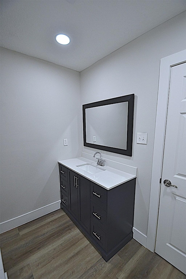 bathroom featuring baseboards, recessed lighting, wood finished floors, and vanity