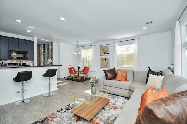 living room featuring recessed lighting, an inviting chandelier, and light wood-type flooring