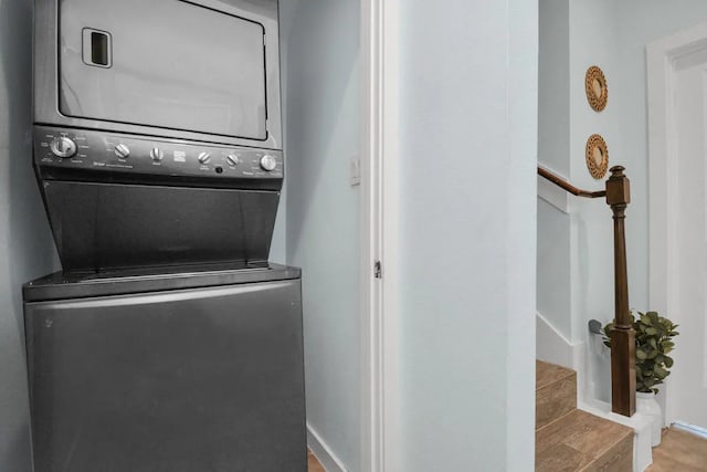 washroom with stacked washer / dryer, laundry area, and baseboards