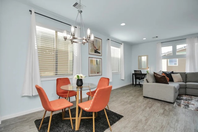 dining area with light wood finished floors, a notable chandelier, a wealth of natural light, and baseboards